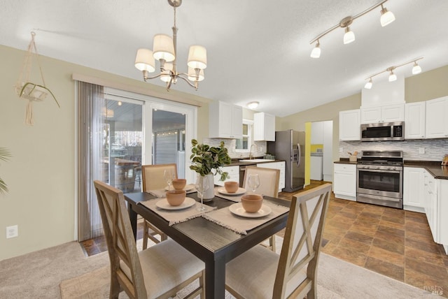 dining space featuring lofted ceiling, sink, a chandelier, and dark colored carpet
