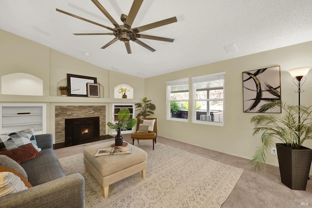 living room featuring ceiling fan, light colored carpet, built in features, a stone fireplace, and a textured ceiling