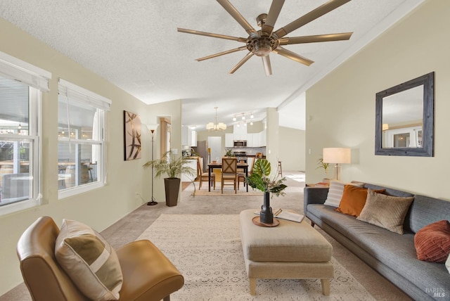 carpeted living room featuring vaulted ceiling, a textured ceiling, and ceiling fan with notable chandelier