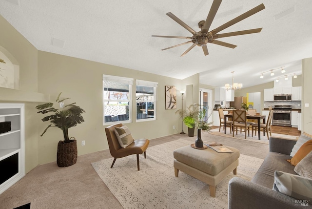 living room featuring ceiling fan with notable chandelier, a textured ceiling, track lighting, vaulted ceiling, and light colored carpet