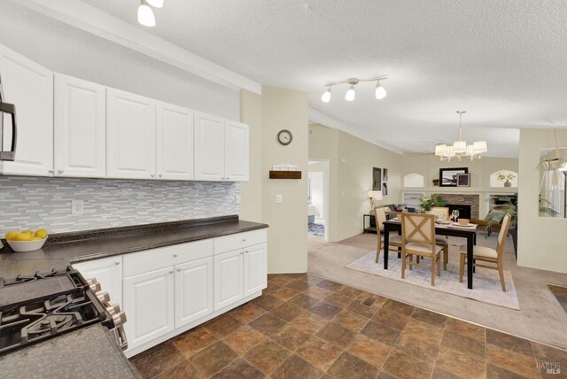 kitchen featuring an inviting chandelier, stainless steel range with gas cooktop, decorative backsplash, a textured ceiling, and white cabinets