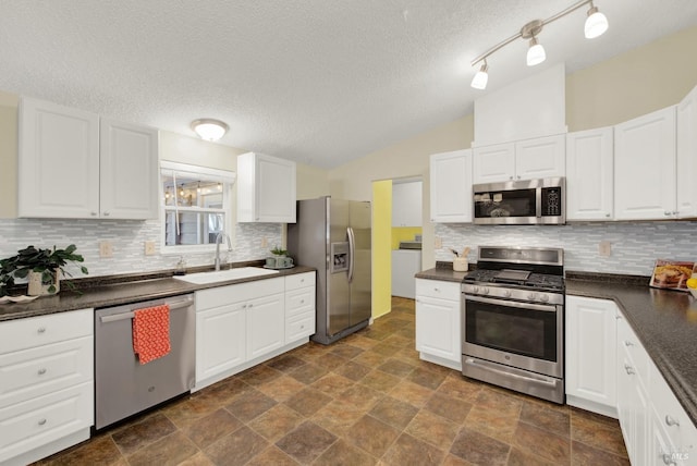 kitchen with a textured ceiling, lofted ceiling, white cabinetry, stainless steel appliances, and sink