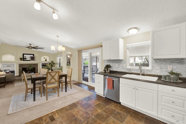 kitchen featuring lofted ceiling, dishwasher, sink, white cabinetry, and hanging light fixtures