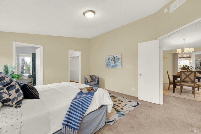 carpeted bedroom featuring a closet, a spacious closet, multiple windows, and a notable chandelier