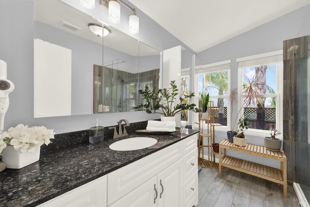 bathroom with vaulted ceiling, a shower with shower door, hardwood / wood-style flooring, and vanity