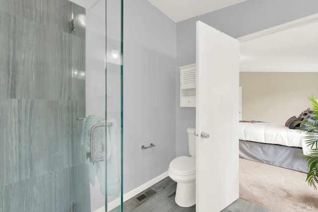 bathroom featuring wood-type flooring, toilet, and a shower with door