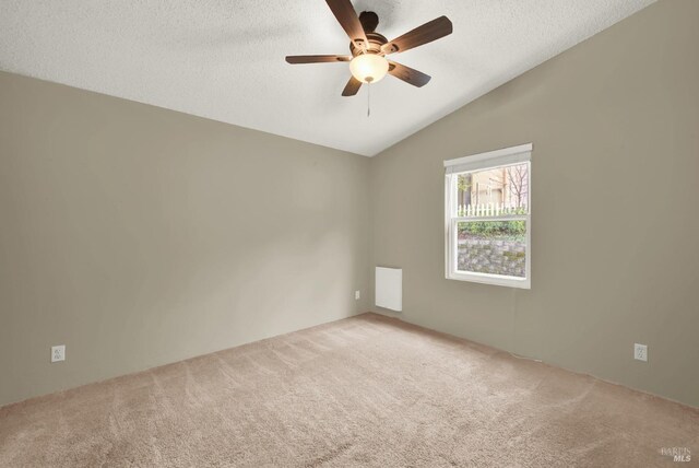 spare room with vaulted ceiling, ceiling fan, carpet, and a textured ceiling
