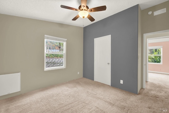 carpeted spare room featuring ceiling fan, a healthy amount of sunlight, and a textured ceiling