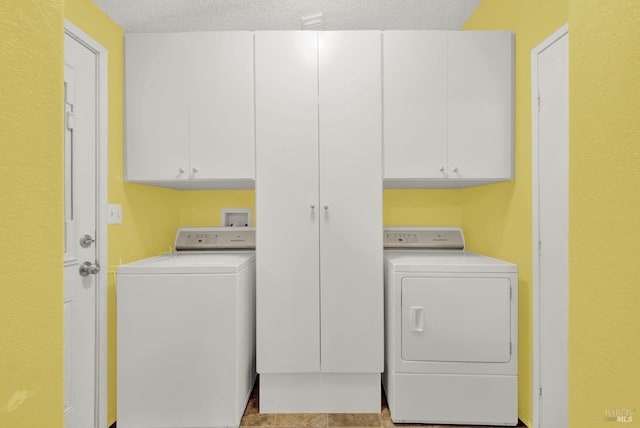 laundry area featuring a textured ceiling, cabinets, and washing machine and clothes dryer