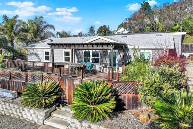 rear view of property with a pergola and a wooden deck