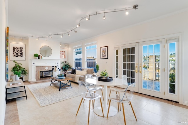 tiled living room with a fireplace, french doors, crown molding, and a healthy amount of sunlight