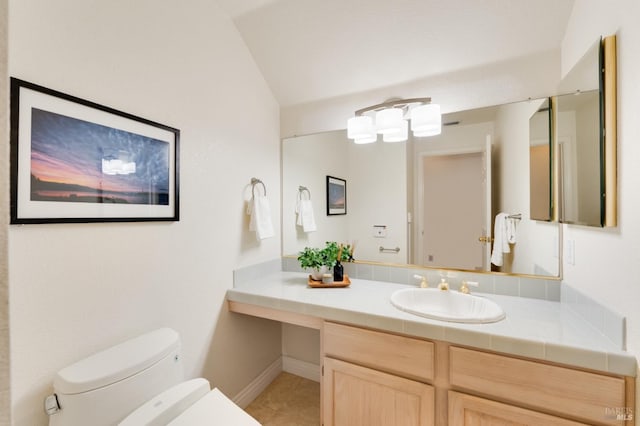 bathroom with tile patterned flooring, vanity, toilet, and vaulted ceiling