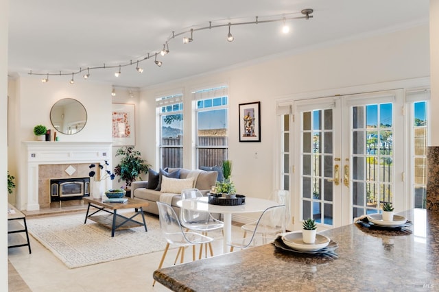 living room featuring a fireplace, crown molding, french doors, and light tile patterned floors