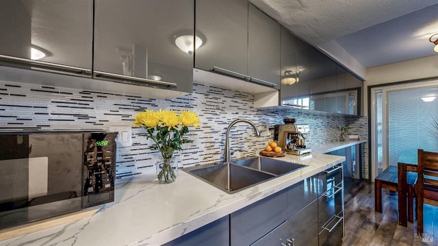 kitchen featuring a sink, decorative backsplash, dark wood-type flooring, black microwave, and modern cabinets