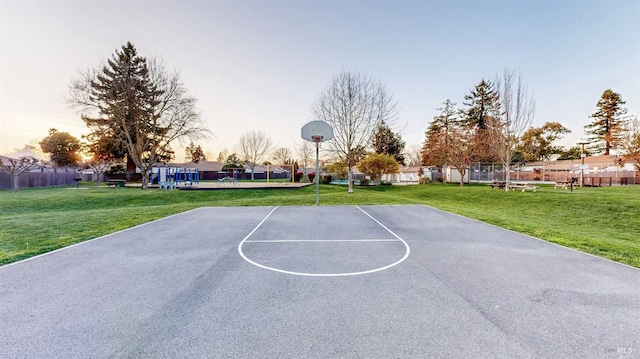 view of basketball court featuring community basketball court, a lawn, and fence