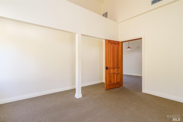 empty room featuring carpet floors and a towering ceiling