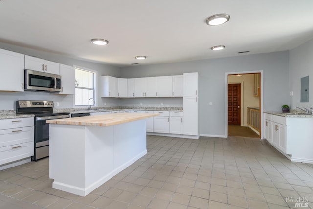 kitchen featuring wood counters, stainless steel appliances, white cabinetry, and a kitchen island