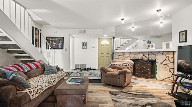 living area with light wood-type flooring, visible vents, and stairway