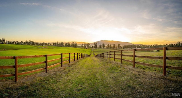 yard at dusk with a mountain view and a rural view