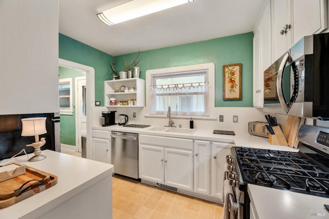 kitchen with stainless steel appliances, white cabinetry, and sink