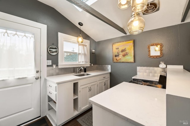 kitchen featuring sink, hanging light fixtures, decorative backsplash, vaulted ceiling with skylight, and white cabinets