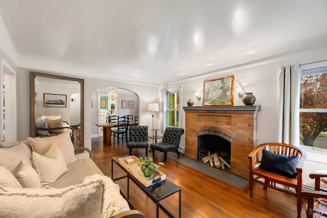 living room featuring dark hardwood / wood-style flooring, a brick fireplace, and ornamental molding