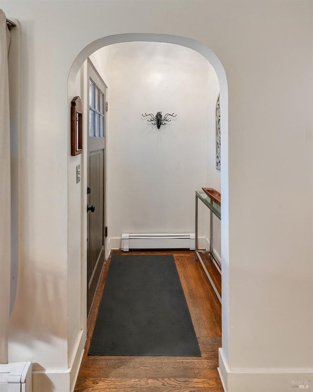 doorway to outside with dark wood-type flooring and a baseboard heating unit