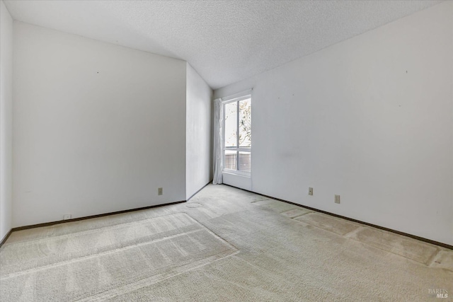 empty room with light colored carpet and a textured ceiling