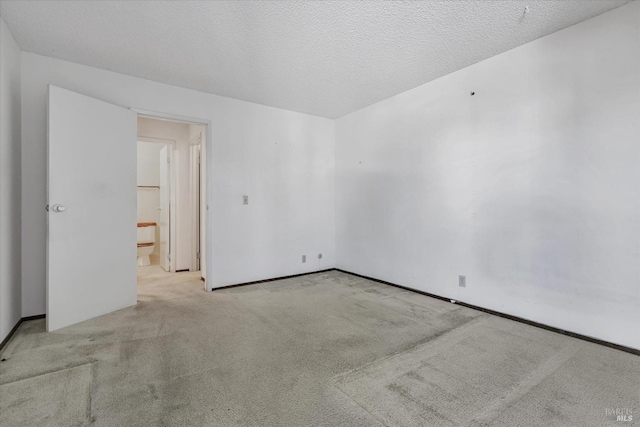 spare room featuring light colored carpet and a textured ceiling