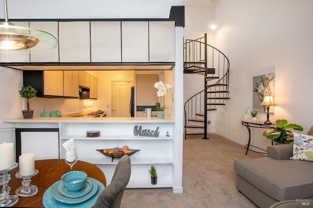 kitchen featuring light carpet, hanging light fixtures, and stainless steel refrigerator