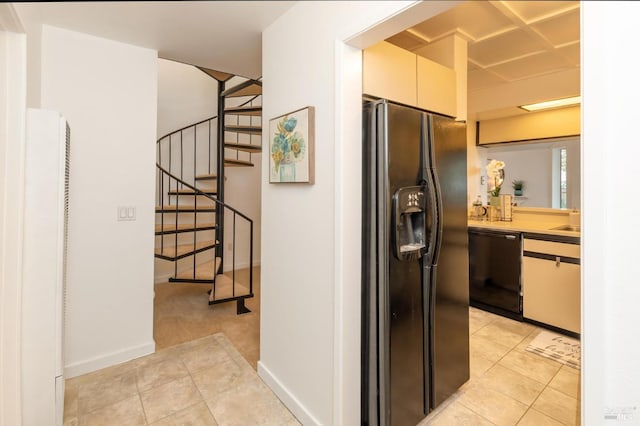 interior space with light tile patterned floors, refrigerator with ice dispenser, and black dishwasher