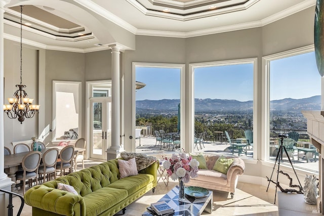 sunroom / solarium with a raised ceiling, ornate columns, a mountain view, and a chandelier