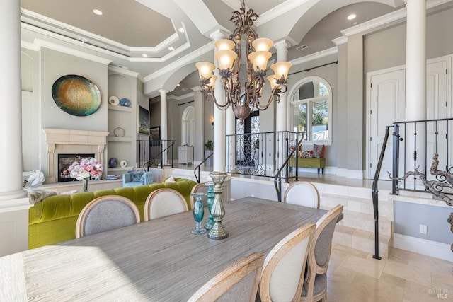 dining area with crown molding, built in features, ornate columns, a tray ceiling, and a chandelier