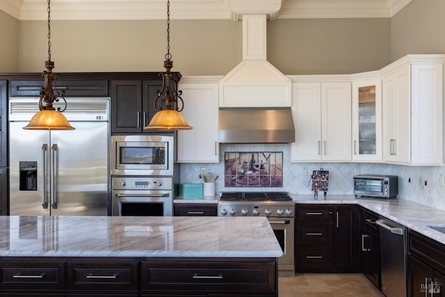 kitchen featuring decorative backsplash, built in appliances, and hanging light fixtures