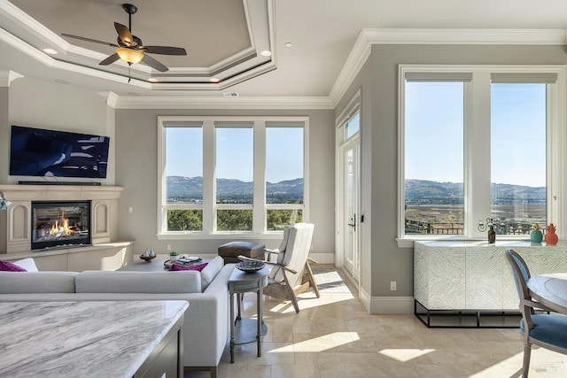 tiled living room with a tray ceiling, ceiling fan, and crown molding