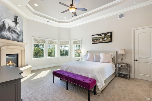 carpeted bedroom with a raised ceiling, ceiling fan, a high ceiling, and ornamental molding