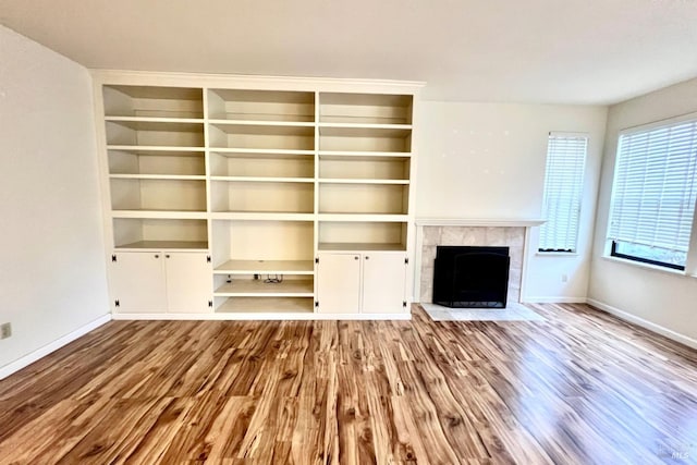 unfurnished living room featuring a healthy amount of sunlight, light wood-type flooring, and a tiled fireplace