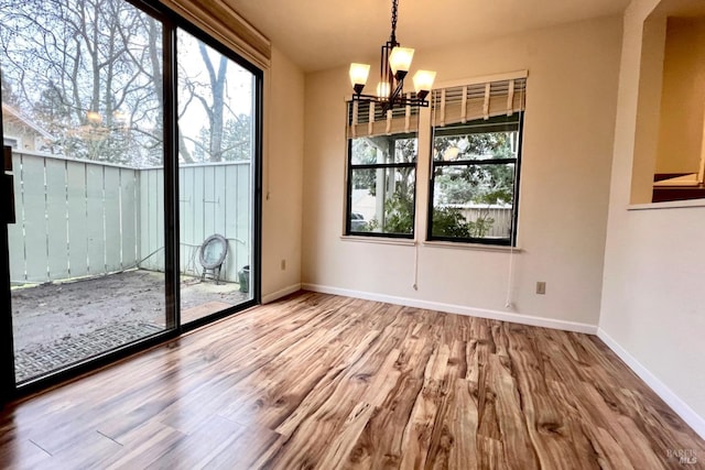 unfurnished dining area with hardwood / wood-style flooring and a notable chandelier