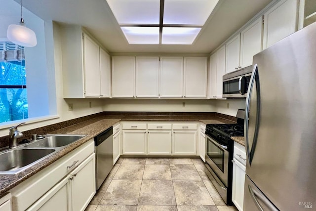 kitchen with appliances with stainless steel finishes, sink, light tile patterned floors, decorative light fixtures, and white cabinets