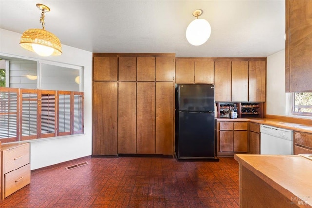 kitchen featuring white dishwasher, dark hardwood / wood-style flooring, black fridge, and hanging light fixtures