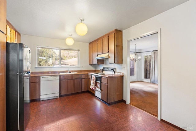 kitchen with decorative light fixtures, white appliances, sink, and an inviting chandelier