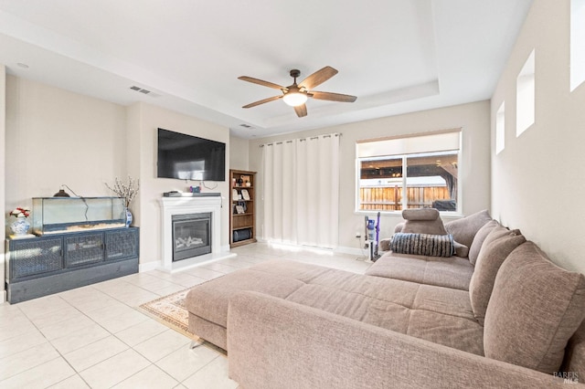 tiled living room featuring a raised ceiling and ceiling fan