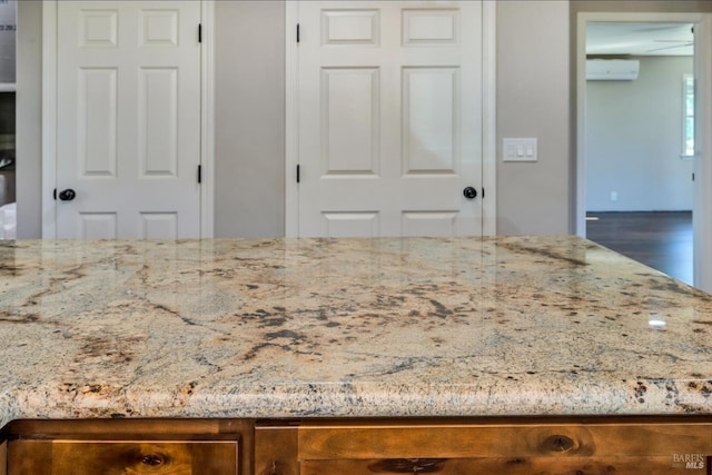 interior space with a wall unit AC and light stone countertops