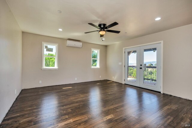 empty room with a wall mounted AC, french doors, ceiling fan, and dark wood-type flooring