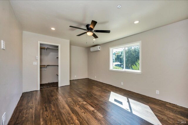 spare room featuring an AC wall unit, ceiling fan, and dark wood-type flooring