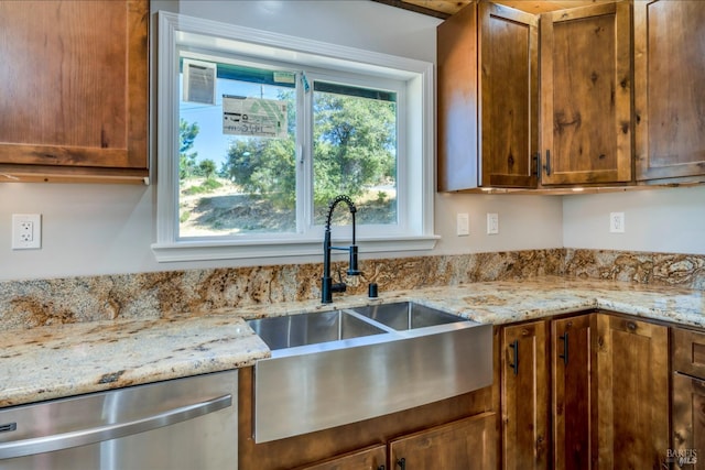 kitchen featuring light stone countertops, dishwasher, and sink