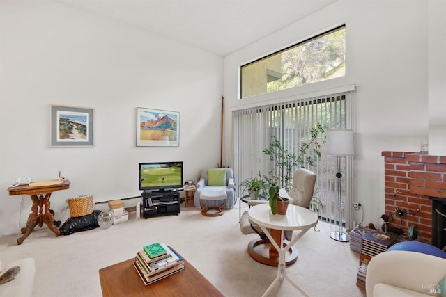 living room featuring carpet flooring, a wealth of natural light, a high ceiling, and a brick fireplace