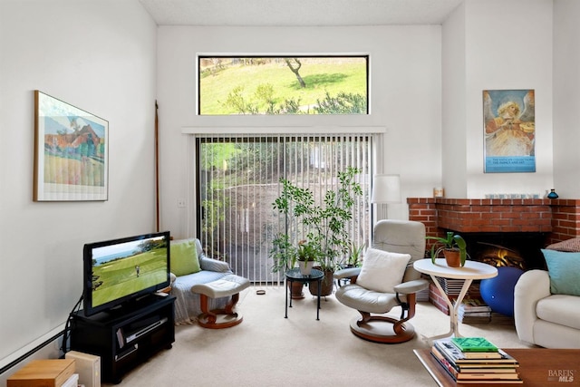 sitting room with carpet floors, a baseboard radiator, a high ceiling, and a brick fireplace