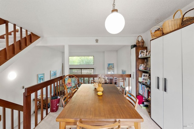 carpeted dining space featuring a textured ceiling