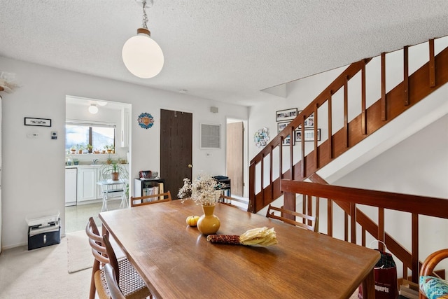 carpeted dining space featuring a textured ceiling